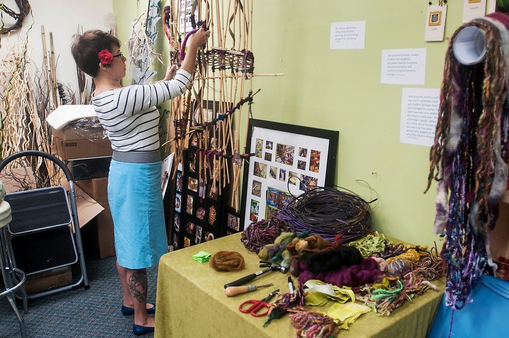 	<p>Lansing resident and print-making artist Kimberly Lavon adds her part to the community weaving piece Sept. 8, 2013, at Grove Gallery &amp; Studios, 325A Grove St. The theme of the five-year anniversary is &#8220;Celebrating Survival.&#8221; The piece shown has been worked on by<br />
community and gallery members. It incorporates their advice and own survival stories. The piece will be sold and partial proceeds will go to the Arts Council of Greater Lansing. Margaux Forster/The State News</p>