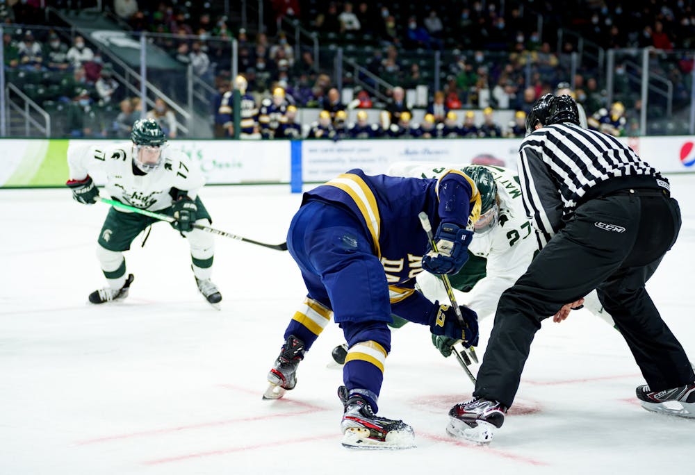 <p>A face-off between Michigan State senior Mitchell Mattson and Notre Dame freshman Hunter Strand with Michigan State sophomore Kyle Haskins in the back on Feb. 19, 2022. Spartans lost 4-2 against Notre Dame.</p>