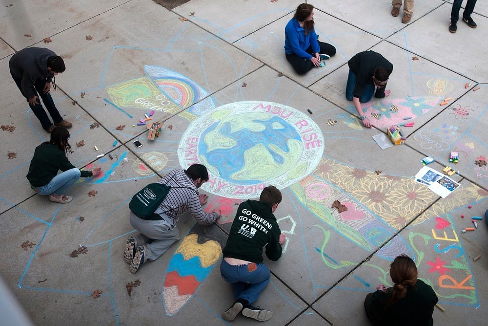 <p>Students draw with chalk on April 22, 2014, outside Bailey Hall, to make a mandala for the RISE program. The program is for students who are interested in environmental sustainability studies who are considering a minor in the subject. Betsy Agosta/The State News</p>