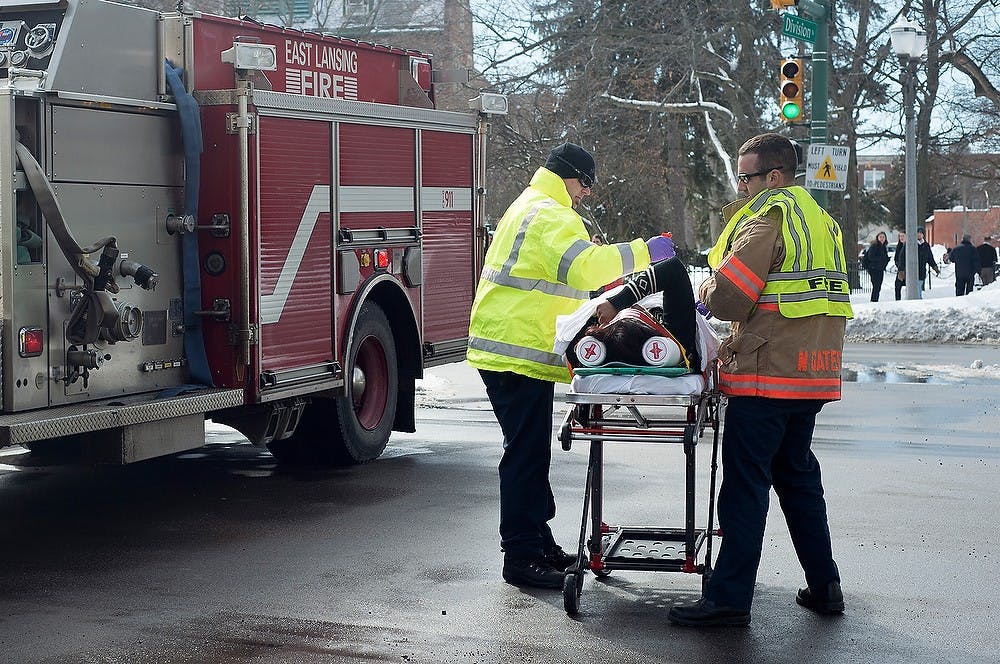 <p>Paramedics tend to a woman who was hit by a CATA bus March 13, 2014, near the corner of Grand River Avenue and Division Street. Julia Nagy/The State News</p>