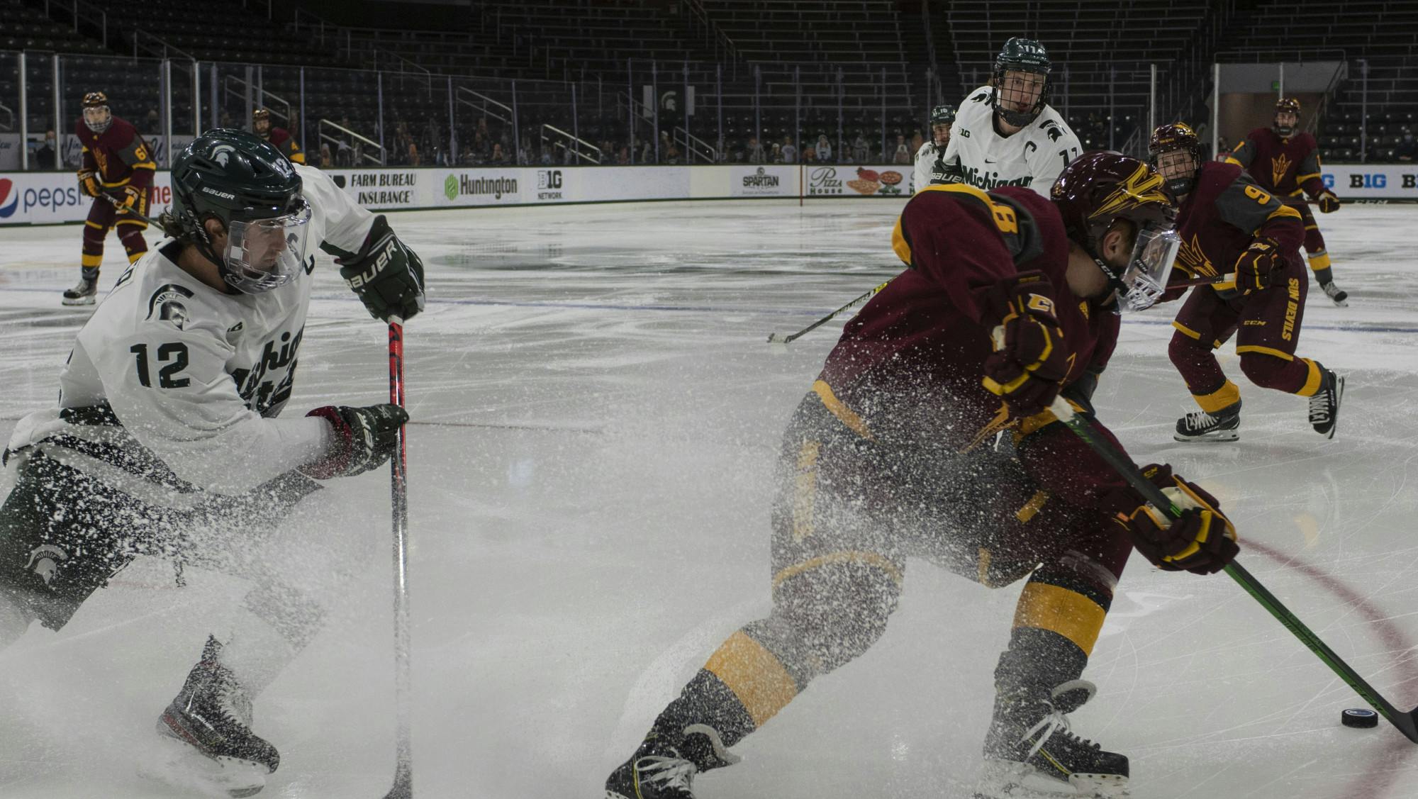 <p>Senior right defenseman Tommy Miller (12) fights to regain possession of the puck in the first period. The Spartans triumphed against the Sun Devils, 2-0, on Nov. 20, 2020.</p>