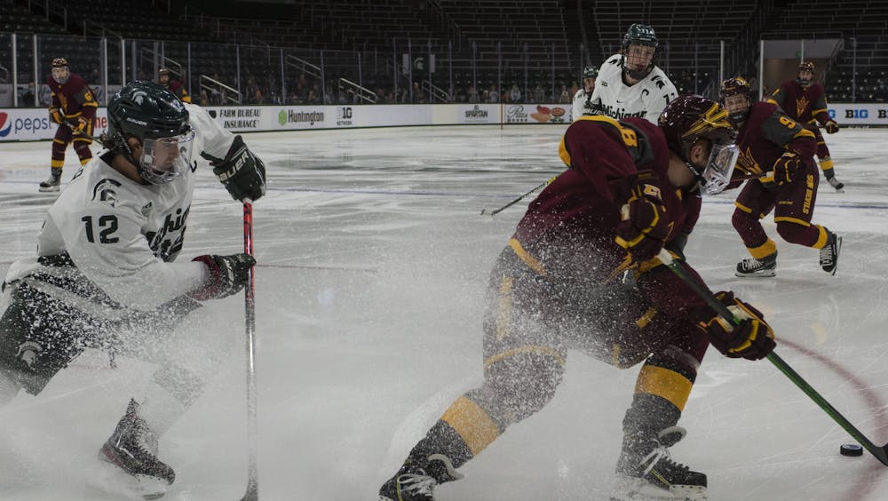 <p>Senior right defenseman Tommy Miller (12) fights to regain possession of the puck in the first period. The Spartans triumphed against the Sun Devils, 2-0, on Nov. 20, 2020.</p>
