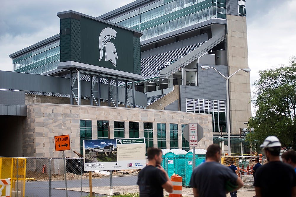 <p>Construction workers stand outside of Spartan Stadium after being evacuated due to a bomb threat July 2, 2014. A tweet from Alumni Association head Scott Westerman stated that all employees within the building were accounted for. Danyelle Morrow/The State News</p>