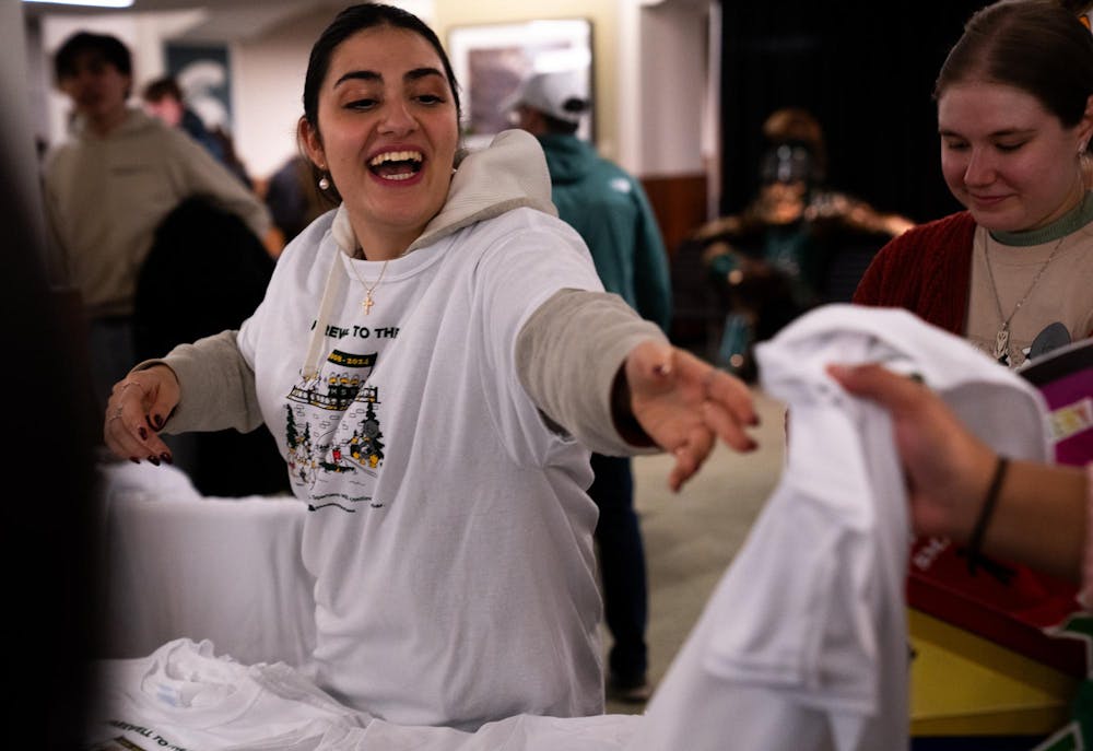 Michigan State human biology junior Christina Rayis passes out shirts at the student union during the Alcohol and Other Drugs Program's Farewell to the Flock event on Dec. 2, 2024.