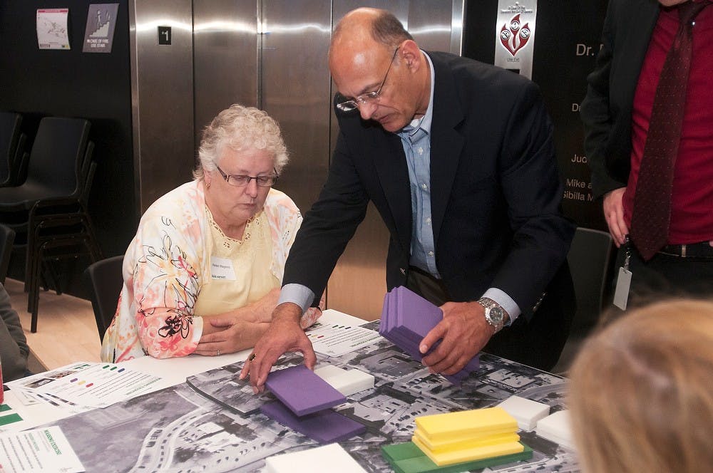 	<p>East Lansing resident Helen Hagens and Delta Township and group mediator Rick D&#8217;Alesandro put building blocks in possible future structure areas Oct. 16, 2013, at the Eli and Edythe Broad Art Museum. The group invited members of the public to give their input for the second Park District charrette. Margaux Forster/The State News</p>