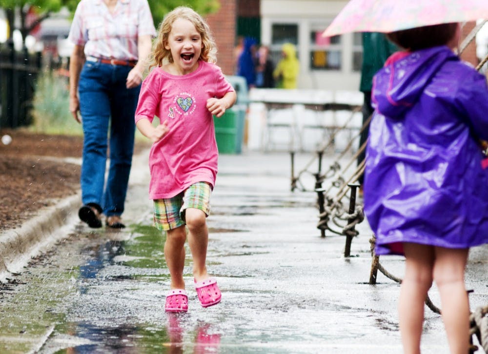 <p>Grand Ledge resident Madeline Gooley, 6, runs through puddles as the rain lets up Sunday at the Great Lakes Folk Festival held in East Lansing. </p>