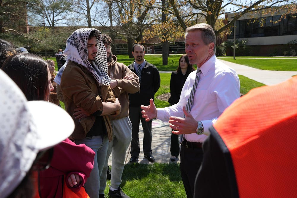 MSU president Kevin Guskiewicz converses with a student protester during a Gaza solidarity encampment in People’s Park on April 25, 2024.