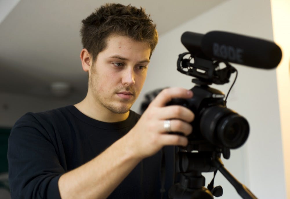 Media arts and technology senior Justin Grosjean checks the settings on his camera before filming a segment of a film project at his classmate's apartment on Tuesday afternoon. Grosjean is one of several MSU students that will be featured at the East Lansing Film Featival Nov. 9-17. Lauren Wood/The State News