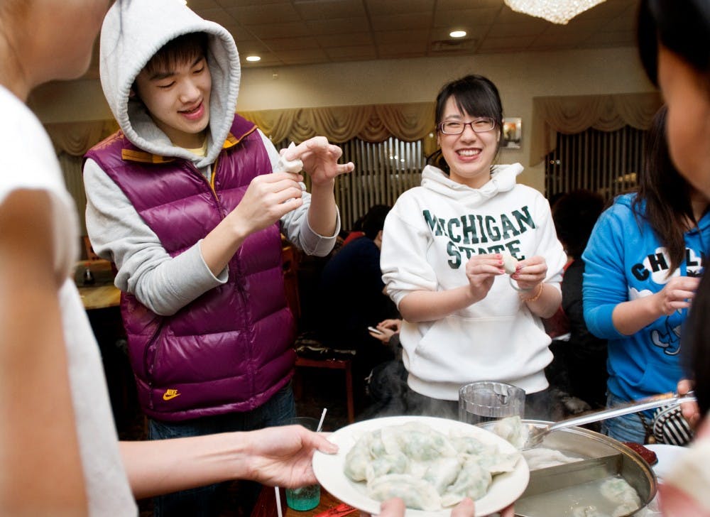 Accounting sophomore Jiajun Lan, right, laughs as business sophomore Teng Cao seals a dumpling at Golden Wok, 2755 E. Grand River Ave. on Friday night as part of the Chinese Undergraduate Student Association's celebration of the Chinese New Year. The group was making shrimp and pork dumplings, and had to postpone their celebration due to the snowstorm that hit earlier in the week. Lauren Wood/The State News