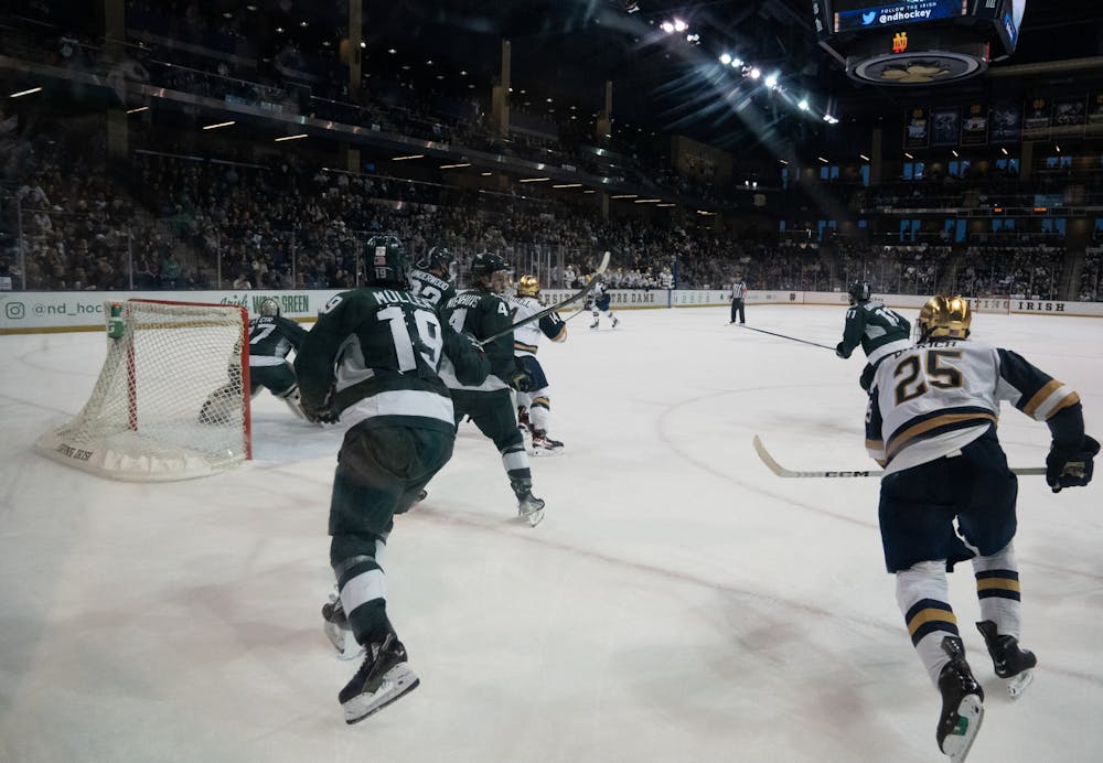 <p>Spartan forward Nicolas Müller (left) and Fighting Irish forward Solag Bakich skate hard from the corner to catch up with the play on Saturday, March 4, 2023 at Compton Family Ice Arena in Notre Dame, IN. MSU defeated Notre Dame 4-2.</p>