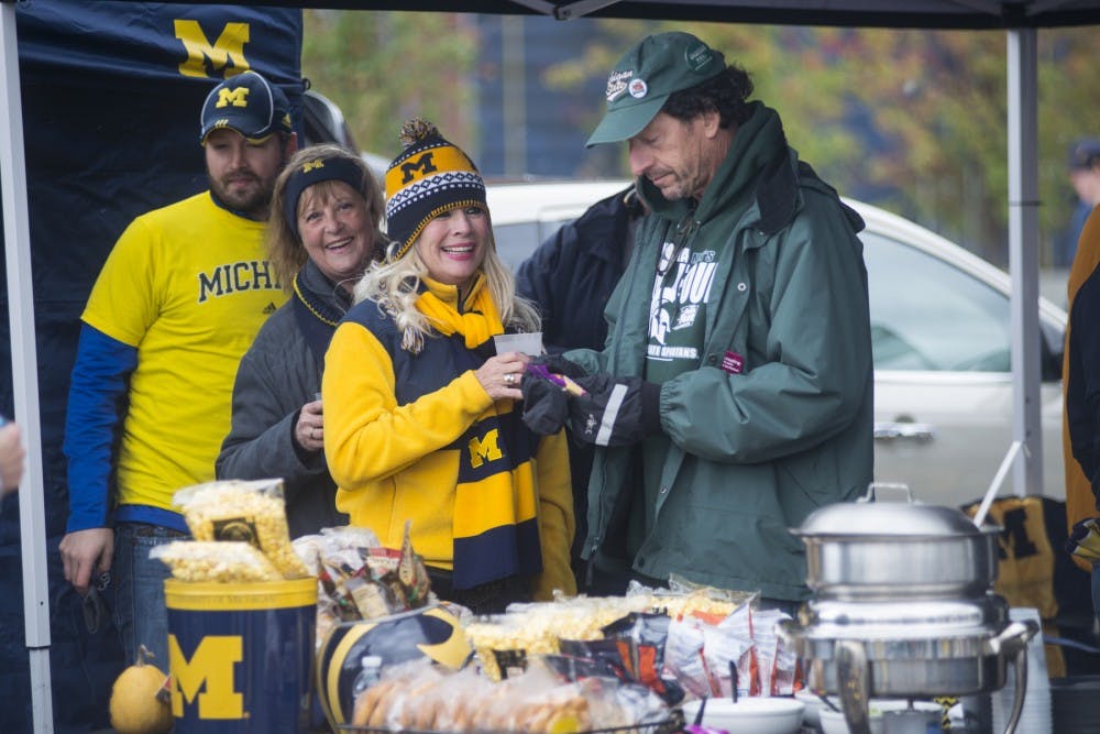 <p>Detroit resident Karen Erookstein, left, watches as Bloomfield, Mich. resident Larry Gaynor, right, gets something to eat on Oct. 17, 2015, prior to the game against Michigan at Michigan Stadium in Ann Arbor. Hundreds of Spartans flocked to Ann Arbor to support the Spartans at the rivalry game. </p>