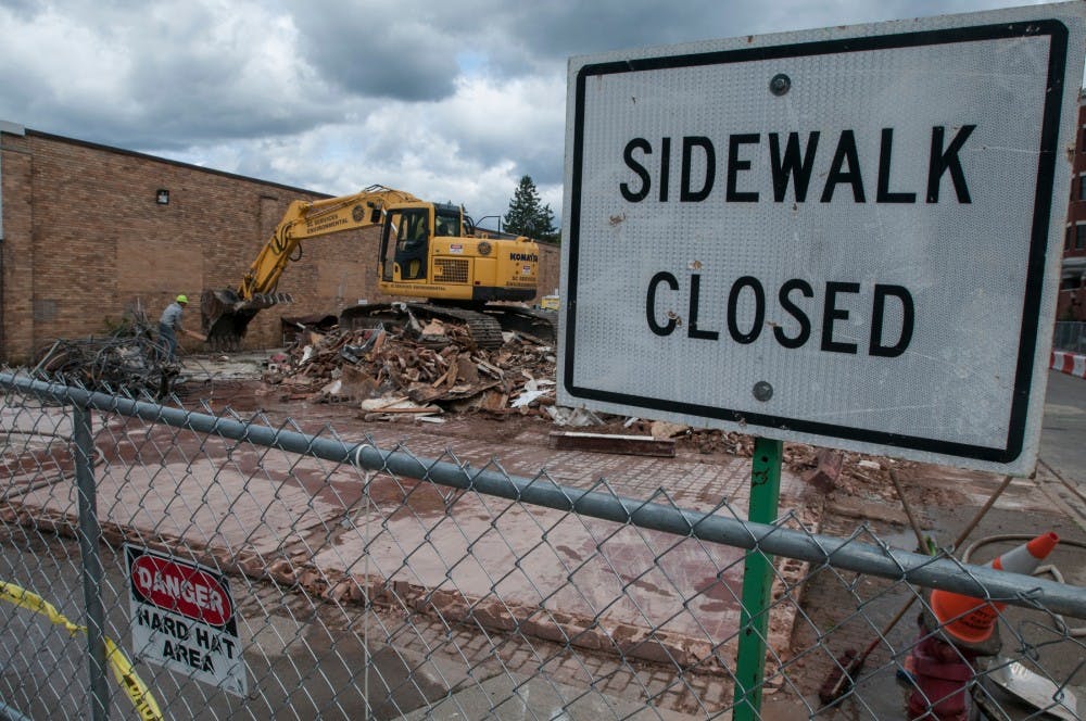 Construction works clear rubble at 565 Grand River Ave., after the building was demolished on Sept. 27, 2016. 