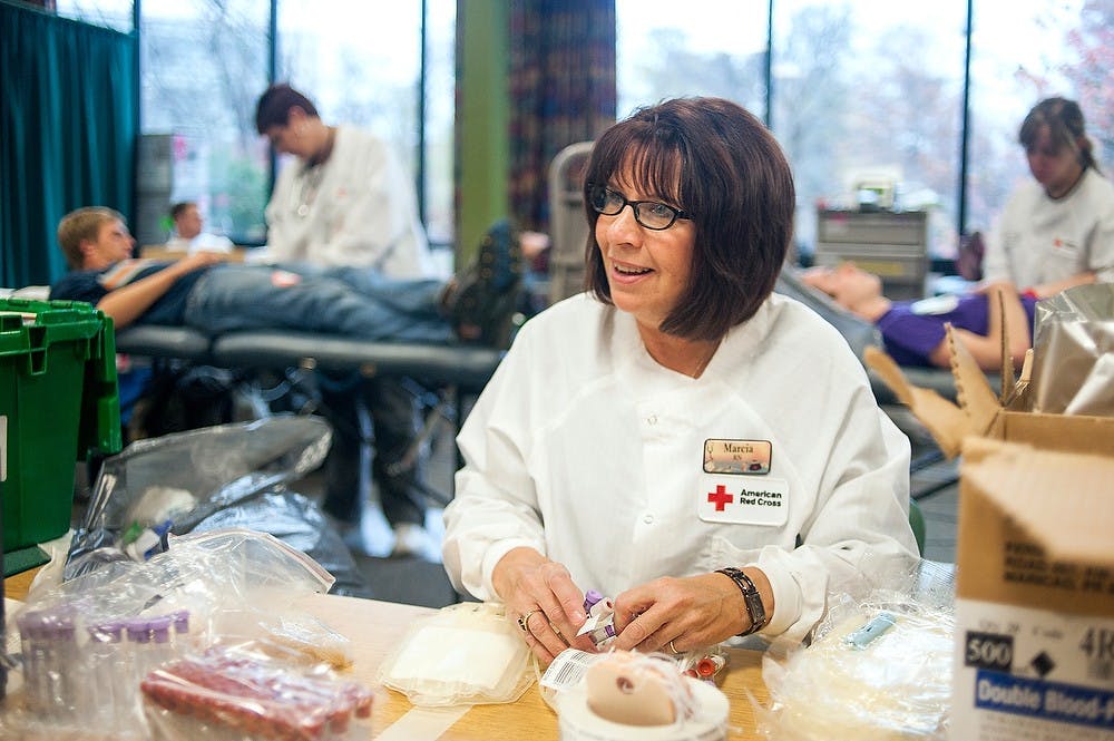 Supervisor Marcia Price shares a laugh with collection technician Anca Potroanchenu, not pictured, on Tuesday afternoon, Oct. 30, 2012 at International Center while organizing blood bags organized. The American Red Cross canceled over 300 blood drives in the East Coast due to Hurricane Sandy. Justin Wan/The State News