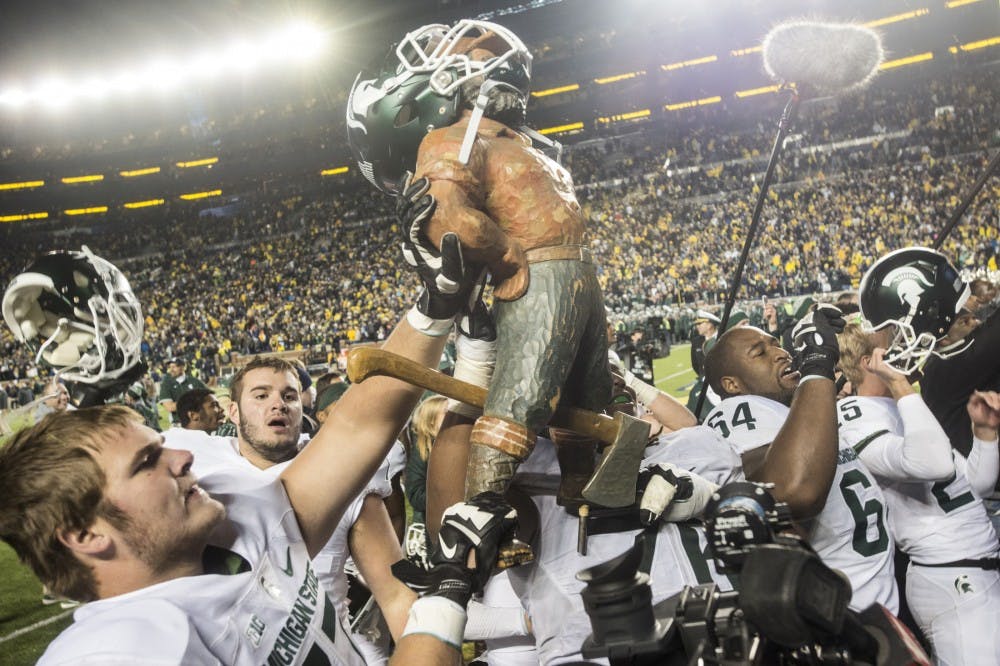 <p>Members of the Michigan State football team present the Paul Bunyan trophy to Spartan fans on Oct. 17, 2015, after the game against Michigan at Michigan Stadium in Ann Arbor. The Spartans defeated the Wolverines, 27-23.</p>
