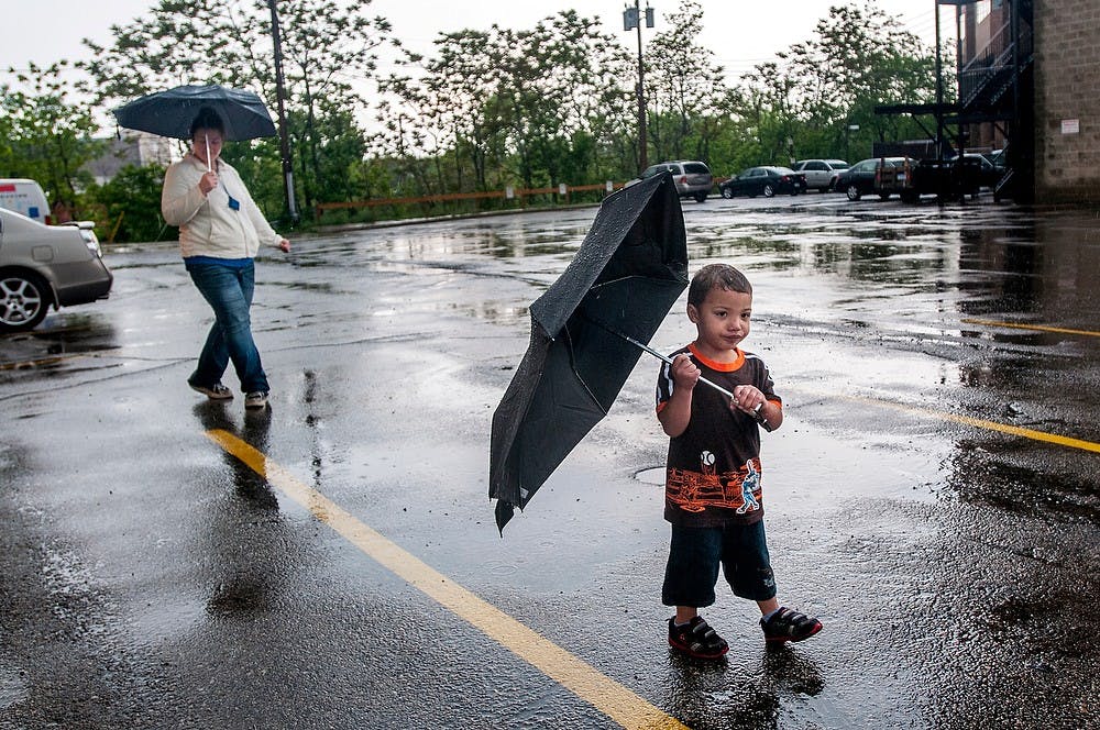 	<p>East Lansing resident Sema&#8217;J Benson, 2, walks with umbrella in hand with his mother Judy Torp behind him, Tuesday, May 28, 2013, in Lansing as the two walk across a parking lot, about to board a Capital Area Transportation Authority, or <span class="caps">CATA</span>, bus that previously was suspended due to a tornado warning issued to Ingham County Tuesday afternoon. Rain and thunderstorms are expected to continue until Sunday. Justin Wan/The State News</p>
