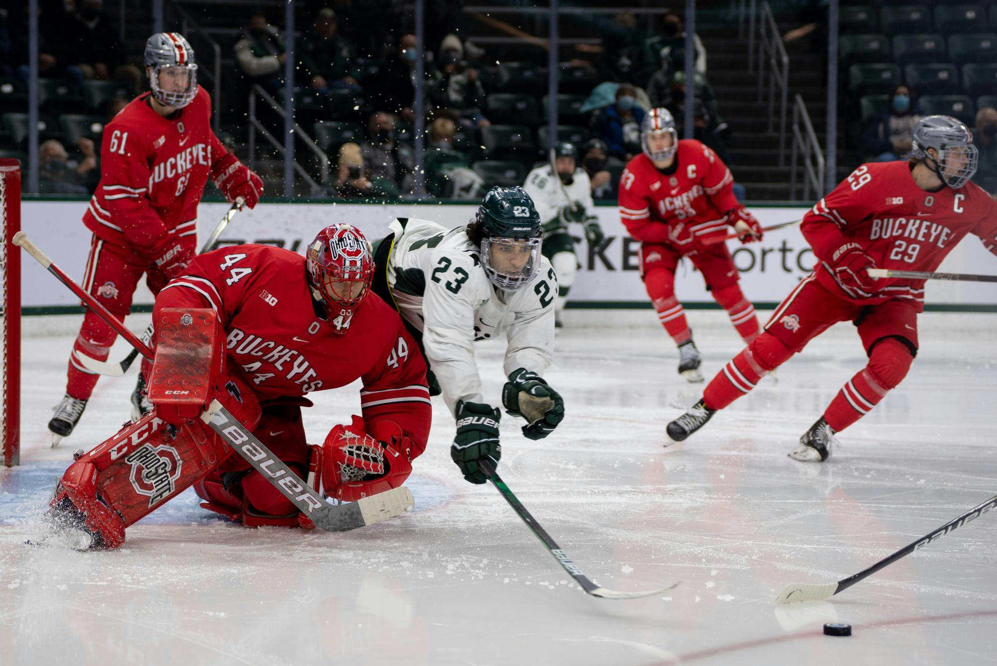 <p>Junior forward Jagger Joshua (23) dives for the puck during the third period. The Spartans fell to the Buckeyes, 4-1, at Munn Ice Arena on Jan. 21, 2022. </p>