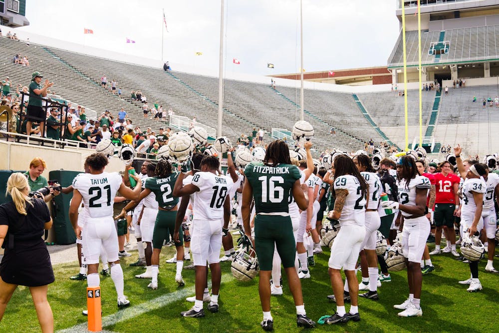 Michigan State University football players celebrate with the band and student section after the spring open practice, held at Spartan Stadium on April 15, 2023.