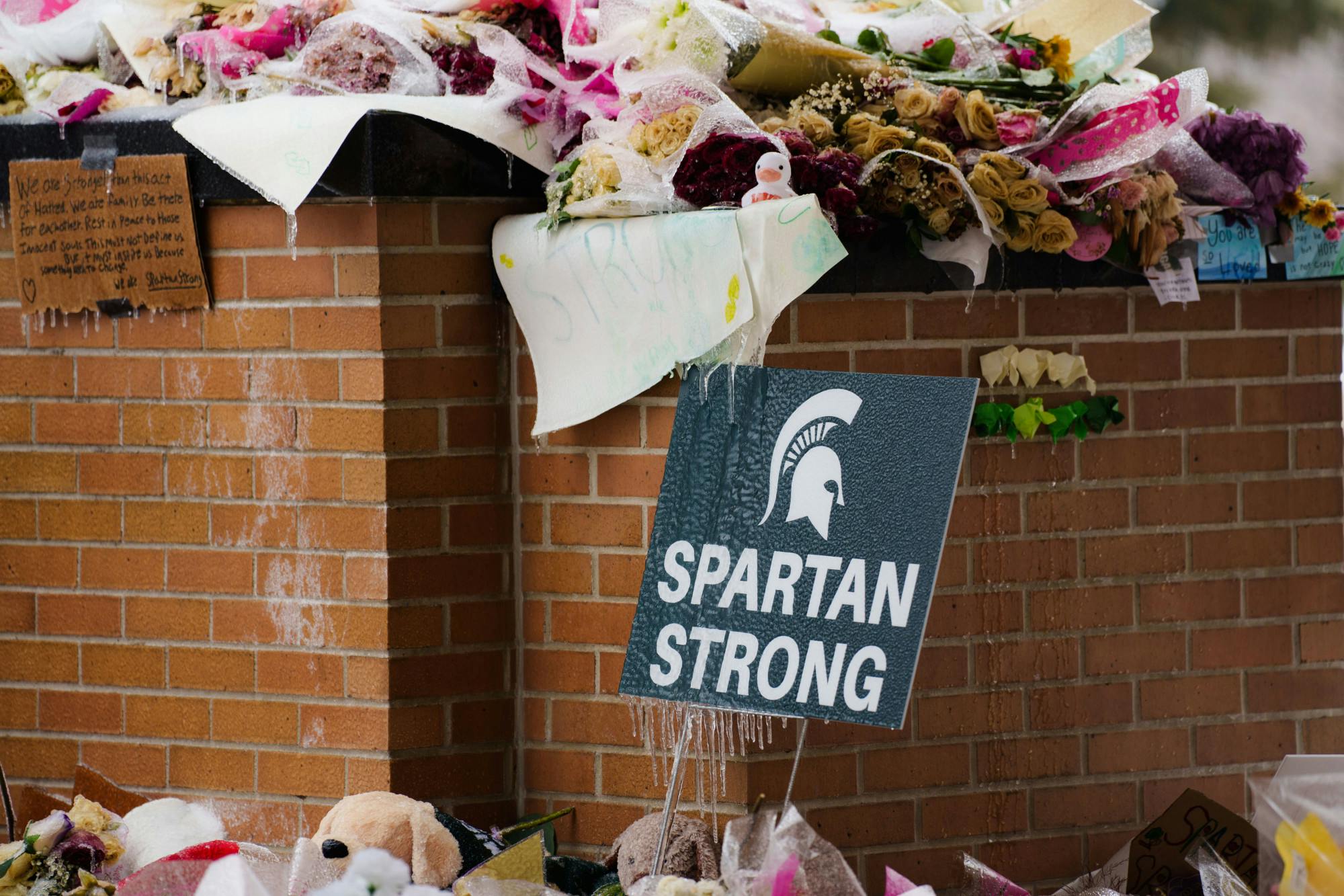 A "Spartan Strong" sign is iced over after a winter storm came through the Michigan State University campus on Feb. 23, 2023. The sign is part of a memorial to students affected by a mass shooting that took place on Feb. 13, 2023.