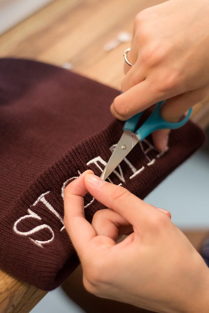 <p>Apparel and textiles junior Kathleen Crowley makes adjustments to an embroidered beanie Oct. 2, 2014, at Sigma Kappa, 518 M.A.C. Ave. Crowley learned to embroider from her aunt in order to start this business. Julia Nagy/The State News</p>