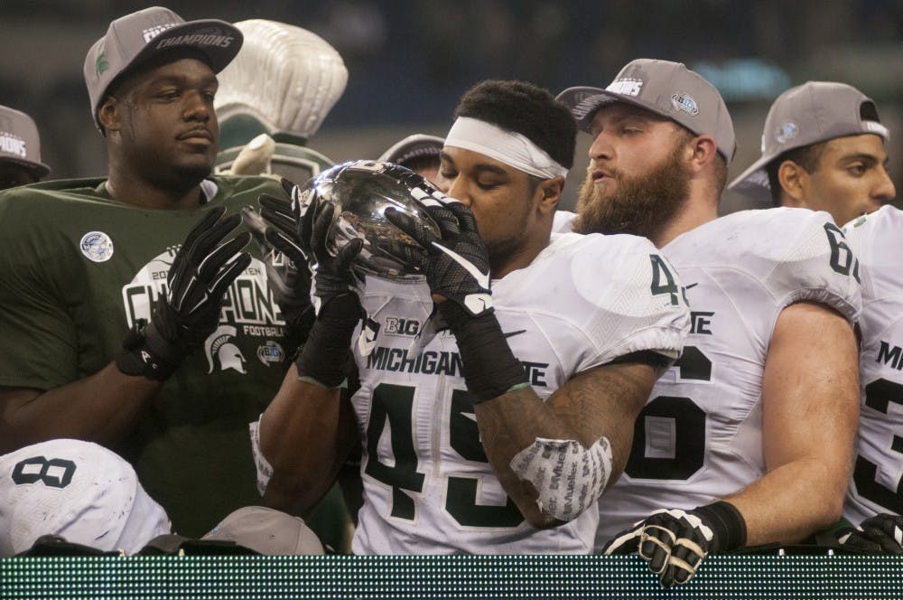 Senior linebacker Darien Harris kisses the trophy on Dec. 5, 2015 after the Big Ten championship game against Iowa at Lucas Oil Stadium in Indianapolis. The Spartans defeated the Hawkeyes, 16-13.