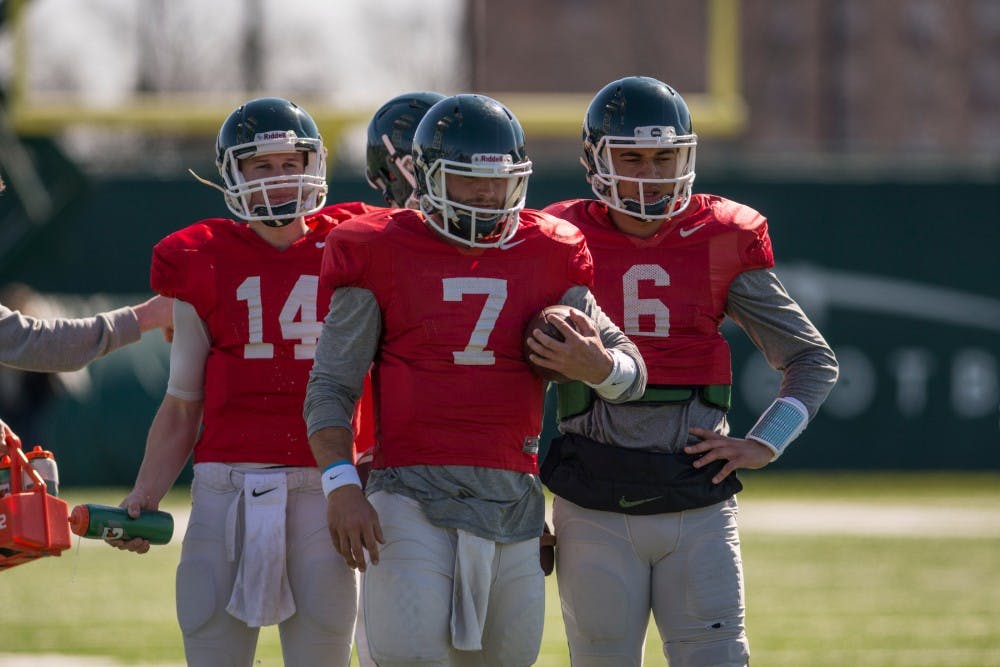 Freshman quarterback Brian Lewerke,14, senior quarterback Tyler O'Connor, 7, and junior quarterback Damion Terry, 6, rest during spring practice on April 5, 2016 at the practice fields behind the Duffy Daugherty Football Building.