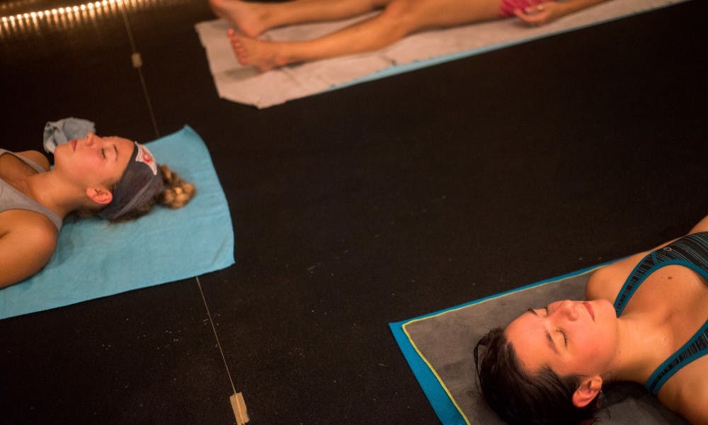 <p>Hospitality business senior Erica Reed, left, and graduate student Cara Feldscher, lower right, meditate at the end of their yoga practice on Sept. 1, 2015, at East Lansing Hot Yoga, 924 Trowbridge Road, in East Lansing.</p>