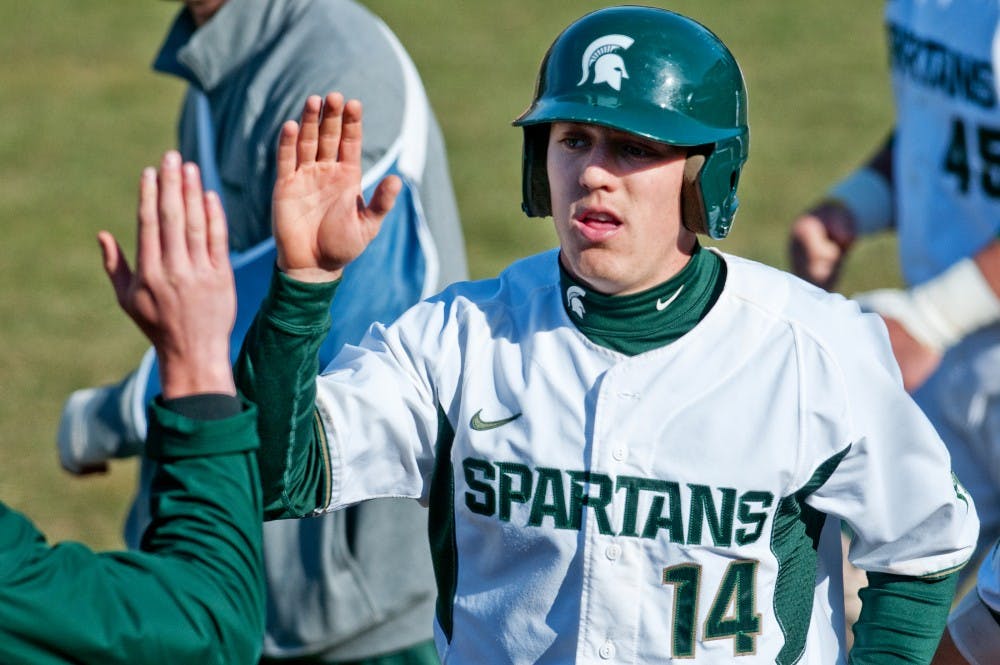 Senior outfielder Brandon Eckerle gets a high five as he comes into the dugout after scoring the Spartan's only run of the game against Central Michigan on Wednesday at McLane Stadium at Kobb Field. Josh Radtke/The State News