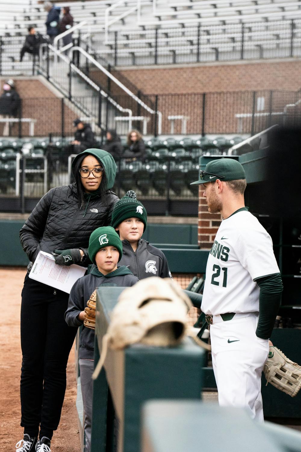<p>Sophomore Jack Frank speaks to two young boys in the dugout, April 19, 2022. </p>