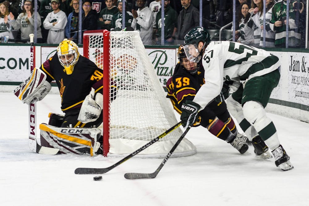 Redshirt senior left defense Jerad Rosburg (57) fights for the puck during the game against Arizona at the Munn Ice Arena on Dec. 14, 2019. The Sun Devils defeated the Spartans, 4-3.