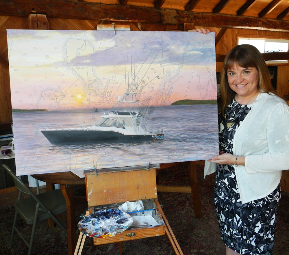 <p>Salina Kalnins poses with one of her nautical chart paintings for the art festival. Courtesy image provided by Kalnins.             </p>