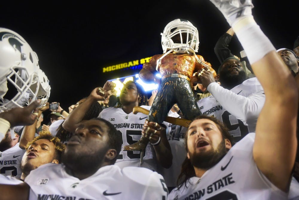 <p>The Spartans hoist the Paul Bunyan Trophy into the air while celebrating the game against Michigan on Oct. 7, 2017 at Michigan Stadium. The Spartans defeated the Wolverines, 14-10.&nbsp;</p>