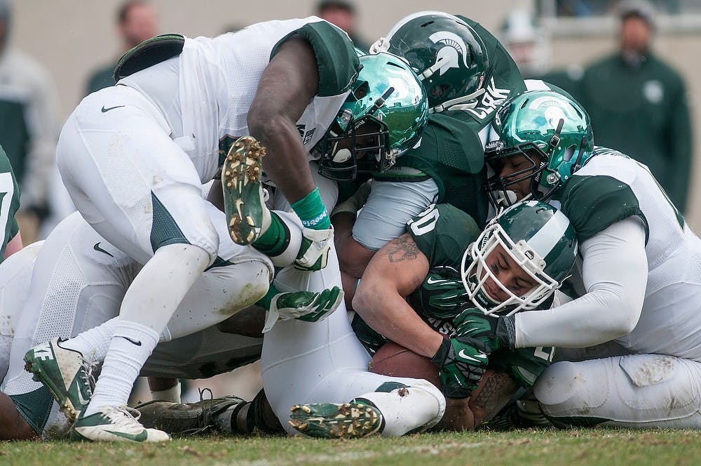 	<p>Junior linebacker Taiwan Jones, left, and senior defensive end Denzel Drone, right, tackle running back Nick Hill during the Green and White Spring Game April 20, 2013, at Spartan Stadium. The White team won 24-17. Julia Nagy/The State News</p>
