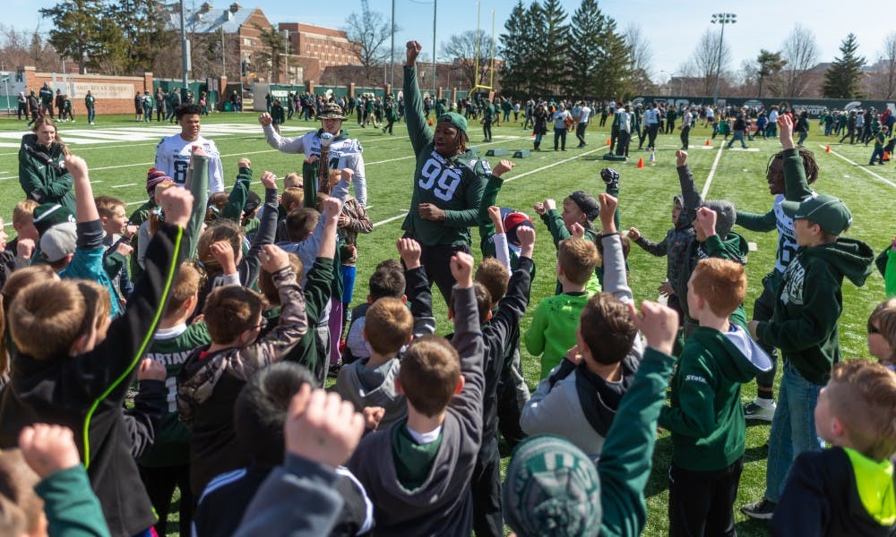 Senior defensive tackle Raequan Williams leads kids in a cheer. The MSU football team held its annual youth clinic at the Duffy Daugherty Football Building on April 13, 2019.