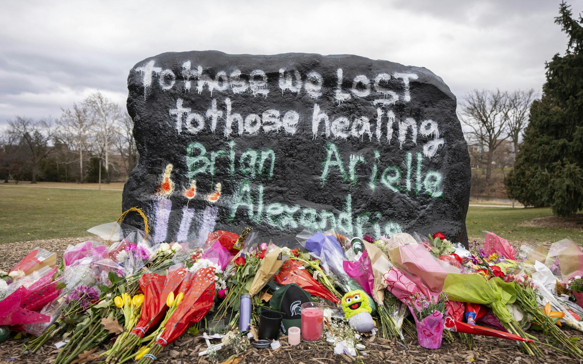 Flowers rest at the foot of the Rock on Farm Lane on Wednesday, Feb. 15, 2023 - two days after the mass shooting in Michigan State University’s north campus. Memorials have spread across campus in honor of Brian Fraser, Alexandria Verner and Arielle Anderson, the three killed on Feb. 13. 