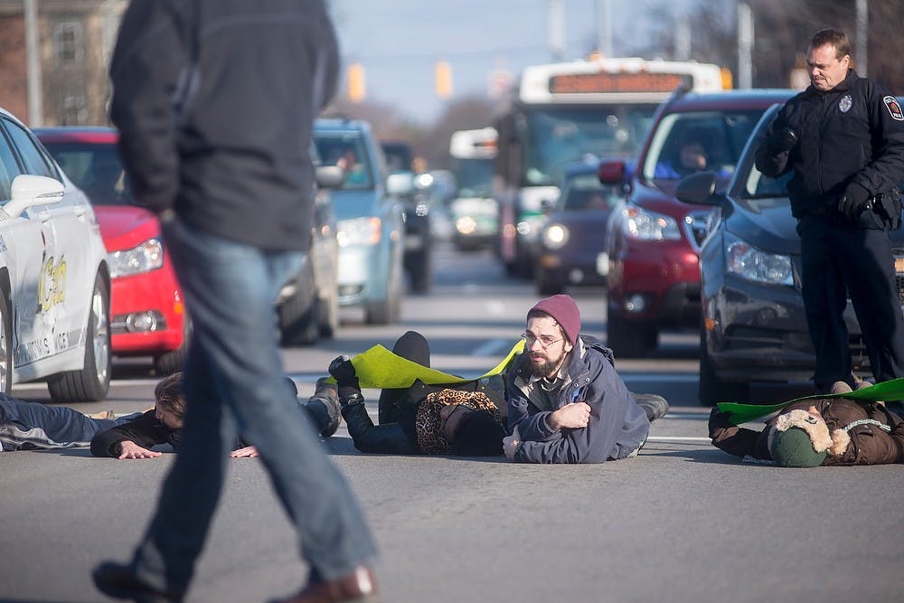 <p>Protesters lie down in the middle of the road and block traffic Dec. 5, 2014, during a protest which went down Grand River Ave., to the MSU Union and ended at Beaumont Tower. The group of students shut down Grand River Ave., in East Lansing by marching and laying down in the middle of the street in protest of police violence against black people. Erin Hampton/The State News</p>