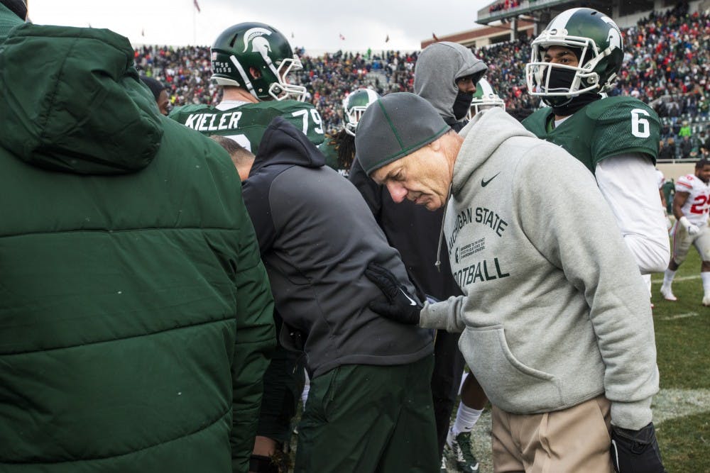 Head coach Mark Dantonio leans in with his team for a prayer after being defeated in the game against Ohio State on Nov. 19, 2016 at Spartan Stadium. The Spartans were defeated by the Buckeyes, 17-16.