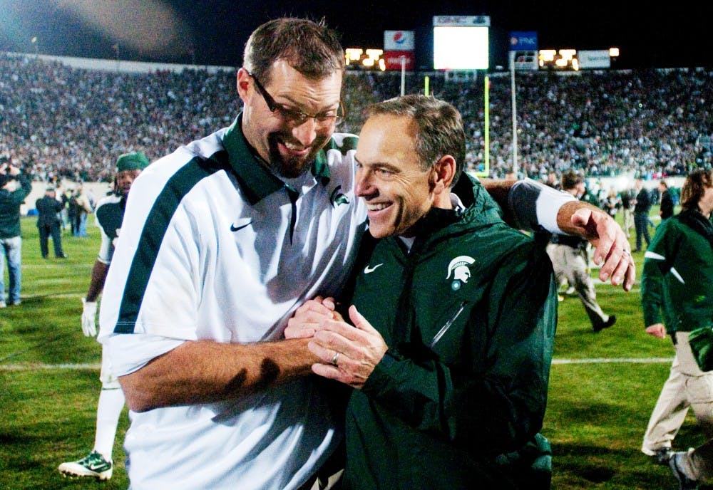 Head coach Mark Dantonio and offensive line coach Mark Staten hug after the emotional win over the Badgers. The Spartans defeated Wisconsin, 37-31, on Saturday night at Spartan Stadium. Josh Radtke/The State News