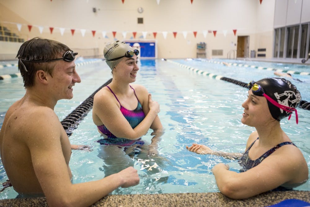 From left to right, finance freshman Josh Ball, astrophysics sophomore Hannah Gallamore and plant biology junior Lucy Schroeder take a break and converse with one another during the MSU Triathlon Club swim practice on Feb. 6, 2017 at IM Sports-Circle.