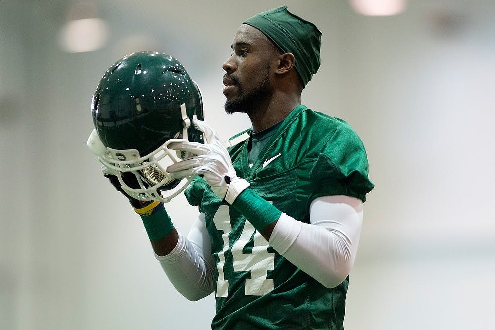 <p>Senior wide receiver Tony Lippett puts on his helmet during a practice March 25, 2014, at the practice field inside the Duffy Daugherty Football Building. Julia Nagy/The State News </p>