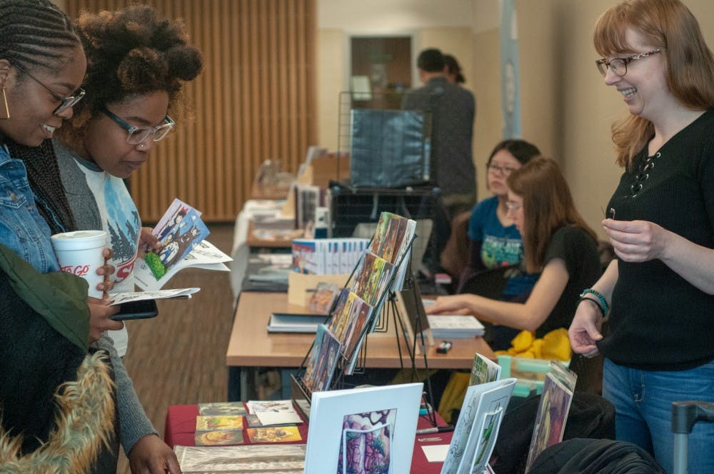 <p>Illustrator and writer Corinne Roberts talks to visitors at the twelfth annual MSU Comics Forum at the MSU Library Feb. 23, 2019.</p>