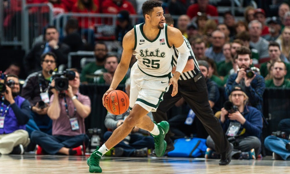 Senior forward Kenny Goins (25) brings the ball up court against Wisconsin. The Spartans beat the Badgers, 67-55, at the United Center on March 16, 2019.