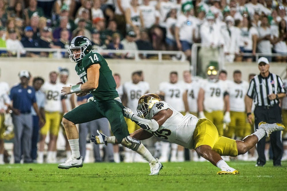 Sophomore quarterback Brian Lewerke (14) runs the ball past Notre Dame defensive line Myron Tagovailoa-Amosa (95) during the game against Notre Dame on Sept. 23, 2017 at Spartan Stadium. The Spartans fell to the Fighting Irish, 38-18. 