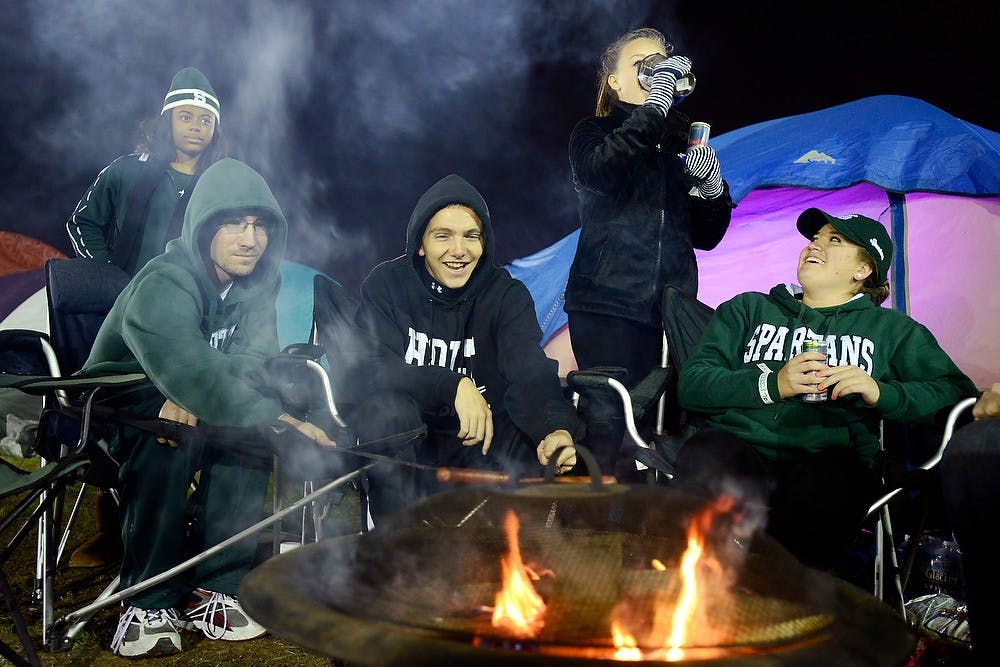 <p>From left, mechanical engineering junior Brian Cobus, business sophomore George Edelman, elementary education freshman Lauren Agnello and kinesiology freshman Kristen Cobus sit around a campfire Oct. 17, 2014, during the Izzone Campout at Munn Field. Hundreds of students battled the cold and rain to sleep outdoors overnight in hopes of getting lower bowl seating. Julia Nagy/The State News</p>