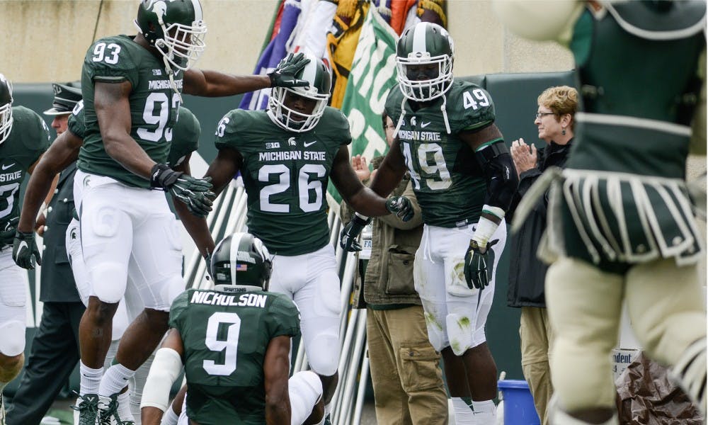<p>Defensive lineman Damon Knox, 93, celebrates with senior safety RJ Williamson, 26, after Williamson's touchdown in the first quarter during a game against Air Force on Sept. 19, 2015, at Spartan Stadium. Williamson scored on a 64-yard fumble return. The Spartans defeated the Falcons, 35-21. Julia Nagy/The State News</p>