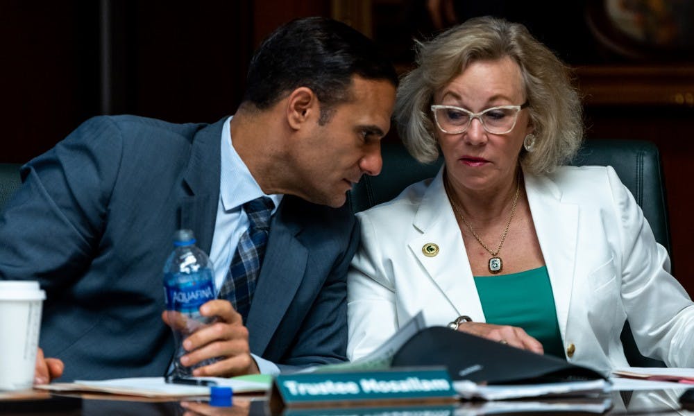 <p>Trustees Brian Mosallam (left) and Melanie Foster (right) speak to each other during an MSU Board of Trustees meeting June 21, 2019 at the Hannah Administration Building. </p>