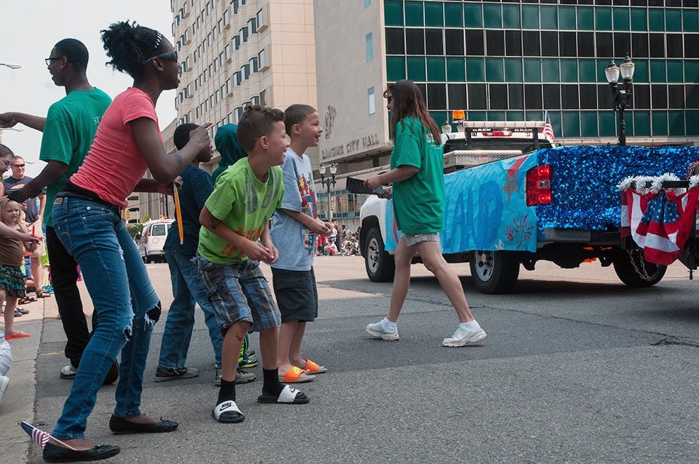 <p>Jayla Edwards, 12, Devin Burke, 9, and Dayvon Burke, 9, await the candy that is given out by the businesses and politicians represented in the parade July 4, 2015 in Lansing. When candy was thrown from a float, there is usually a group of excited children racing to claim their prize. Catherine Ferland/ The State News</p>