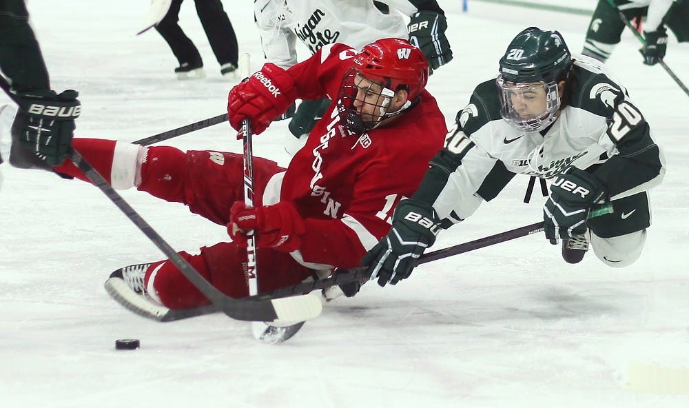 <p>Sophomore forward Michael Ferrantino fights for the puck against Wisconsin forward Nic Kerdiles on March 15, 2014, at Munn Ice Arena. The Spartans were defeated by the Badgers, 4-3. Danyelle Morrow/The State News</p>