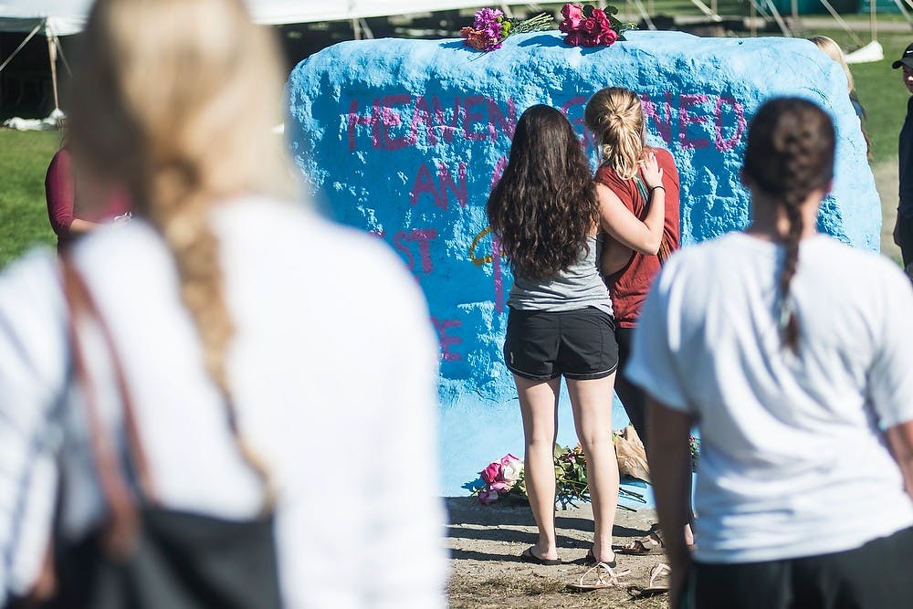 <p>Psychology senior Megan Donohue, left, mourns accounting senior Morgan McGregor with kinesiology senior Kristen Wouters on Sept. 28, 2014, during McGregor's memorial at the Rock on Farm Lane. State News file photo.&nbsp;</p>