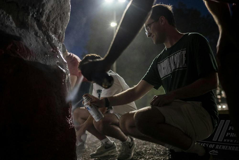 Jacob Tritz, president of MSU Young Americans for Freedom and a senior studying games and interactive media, paints the Rock alongside other members of MSU Young Americans for Freedom and MSU College Republicans during preparations for a 9/11 memorial at Michigan State University in East Lansing, Mich., Thursday, Sept. 10, 2026. The organizations placed 2,977 American flags around the Rock, one for each victim killed in the Sept. 11, 2001, terrorist attacks, to mark the 25th anniversary of the attacks.