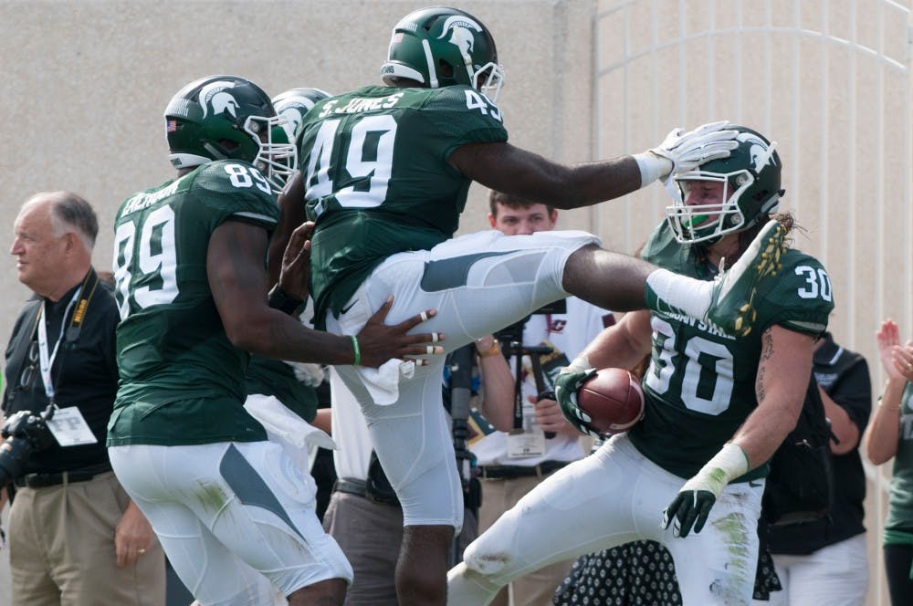 <p>Senior defensive end Shilique Calhoun, 89, and sophomore linebacker Shane Jones, 49, celebrates with junior linebacker Riley Bullough, 30, after he recovered a fumble from Central Michigan in the fourth quarter during the game against Central Michigan on Sept. 26, 2015, at Spartan Stadium. Bullough picked up 13 yards on the play. The Spartans defeated the Chippewas, 30-10. Joshua Abraham/The State News</p>